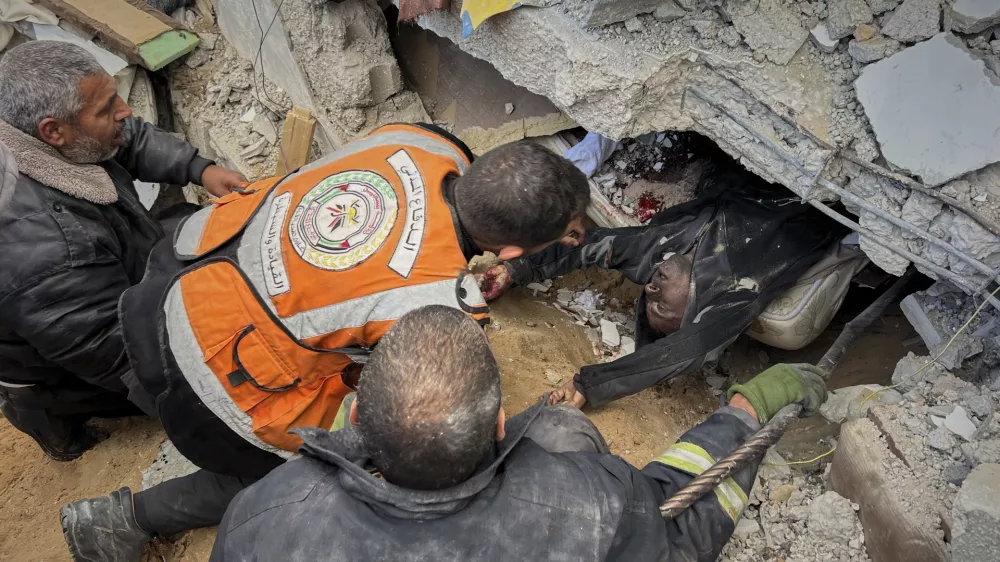 FILE - EDS NOTE: GRAPHIC CONTENT - Rescue workers and volunteers attempt to pull the body of a man from the rubble following an Israeli army airstrike in Khan Younis, southern Gaza Strip, Thursday, March 20, 2025. (AP Photo/Mariam Dagga, File)