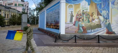 A soldier carries a Ukrainian national flag outside St. Michael's Golden-Domed Monastery, amid Russia's attack on Ukraine, in Kyiv, Ukraine August 25, 2025. REUTERS/Thomas Peter