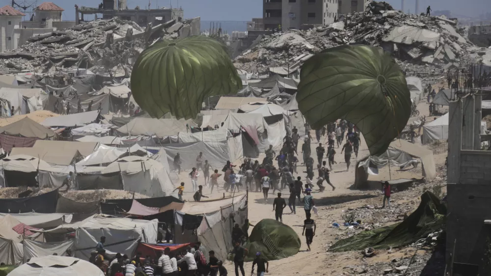 Palestinians rush to collect humanitarian aid airdropped by parachutes into Gaza City, northern Gaza Strip, Aug. 7, 2025. (AP Photo/Jehad Alshrafi)