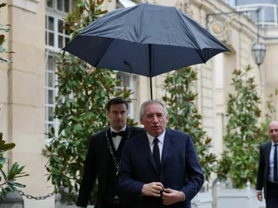 French Prime Minister Francois Bayrou walks under an umbrella as he arrives for a series of consultations with political parties, a week before a confidence vote he is seeking from the National Assembly on the budget issue, at the Hotel Matignon in Paris, France, September 2, 2025. REUTERS/Gonzalo Fuentes