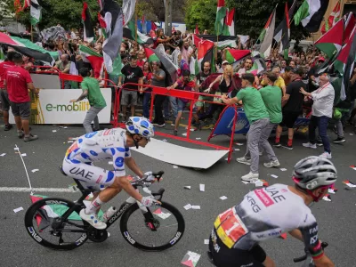 People hold Palestinian flags as they try to disrupt the eleventh stage of the Spanish Vuelta cycling race, from Bilbao to Bilbao, Spain, Wednesday, Aug. 3, 2025. (AP Photo/Miguel Oses)