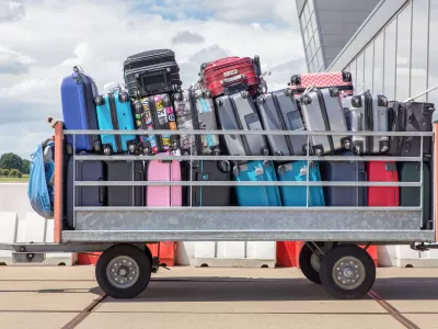 Trailer outside on airport filled with suitcases. When I arrived in Amsterdam on the airport Schiphol I took this image of packed suitcases on a standing trailer. Passengers on vacation take a lot of travel equipment or holiday gear with them. The trailer is parked outside, waiting to be transported to the plane or airplane.