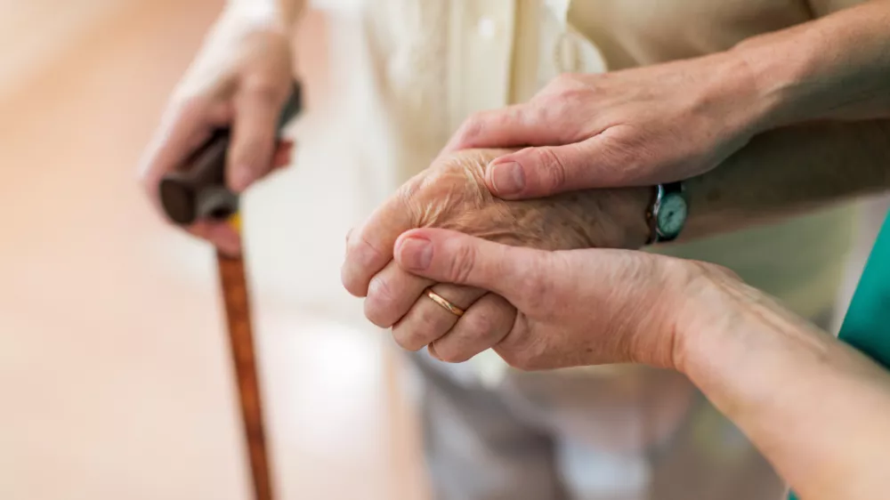 Nurse consoling her elderly patient by holding her hands / Foto: Piksel