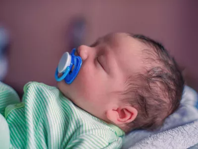 Face profile portrait of a sleeping newborn baby with a pacifier in his mouth
