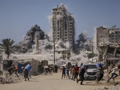 FILE - Palestinians run for cover during an Israeli airstrike on a high-rise building in Gaza City, Friday, Sept. 5, 2025, after the Israeli army issued a warning. (AP Photo/Yousef Al Zanoun, File)