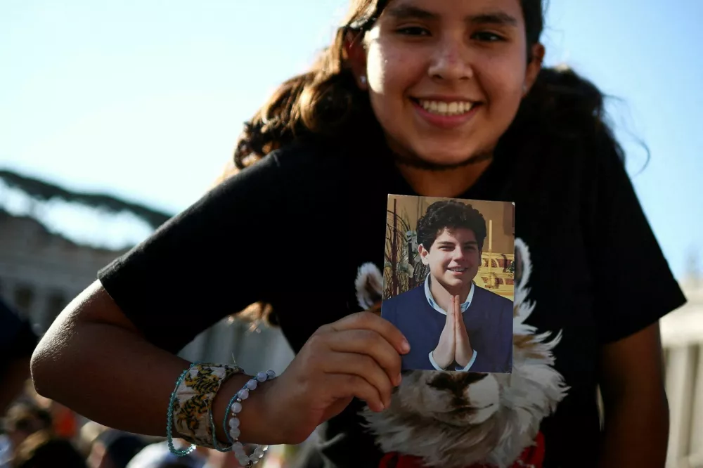 A woman holds a picture of Carlo Acutis on the day Pope Leo XIV leads a Holy Mass for the canonisation of Carlo Acutis, a British-born Italian boy who will become the first millennial to be made a Catholic saint, and Pier Giorgio Frassati, in St. Peter's Square at the Vatican, September 7, 2025. REUTERS/Guglielmo Mangiapane   TPX IMAGES OF THE DAY