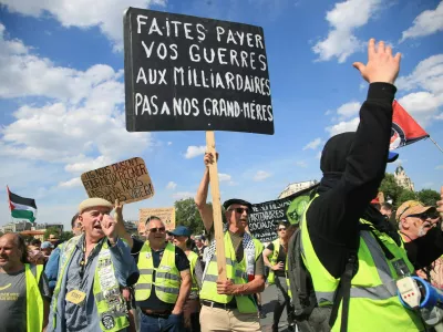 Demonstranti med letošnjimi delavskim praznikom. Na transparentu piše: Za vaše vojne naj plačajo milijarderji, ne naše babice.