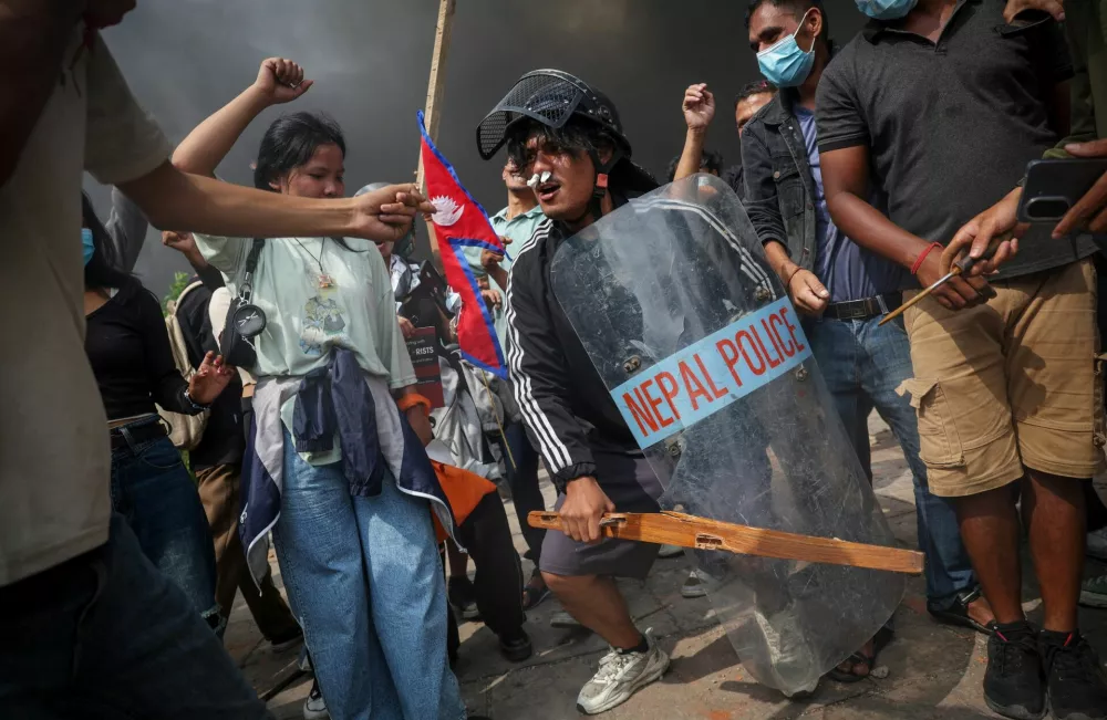 Demonstrators celebrate as smoke rises from a fire set at the Parliament complex during a protest against Monday's killing of 19 people after anti-corruption protests that were triggered by a social media ban, which was later lifted, during a curfew in Kathmandu, Nepal, September 9, 2025. REUTERS/Adnan Abidi