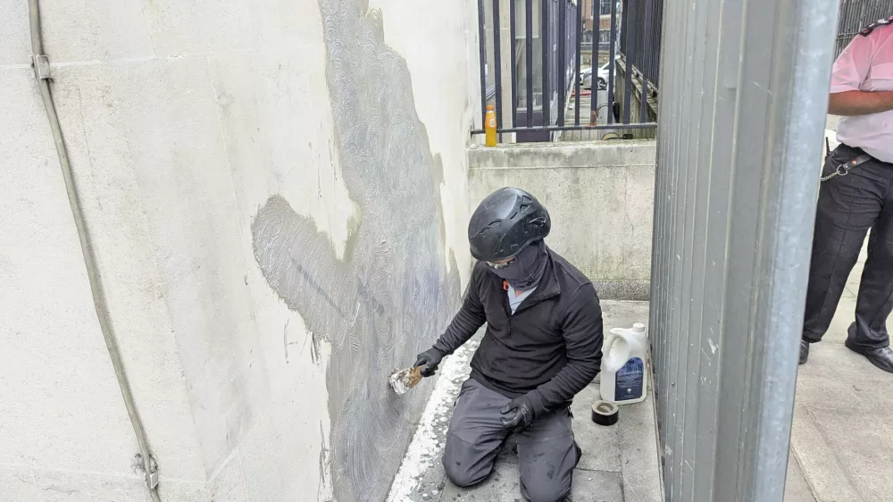 A worker removes the new artwork by Banksy, which shows a judge attacking a protester with a gavel, after it appeared at the Royal Courts of Justice in London on Monday, on Wednesday, Sept. 10, 2025. (Danny Halpin/PA via AP)