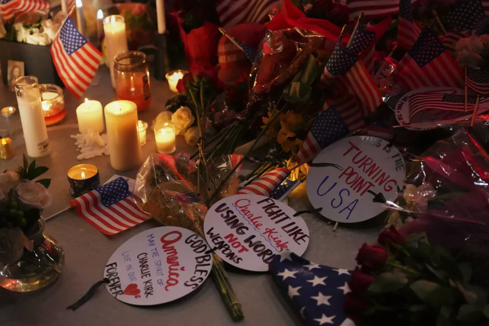 Flags, candles and signs sit at a vigil for Charlie Kirk, the CEO and co-founder of Turning Point USA who was shot and killed, Thursday, Sept. 11, 2025, in Orem, Utah. (AP Photo/Lindsey Wasson)