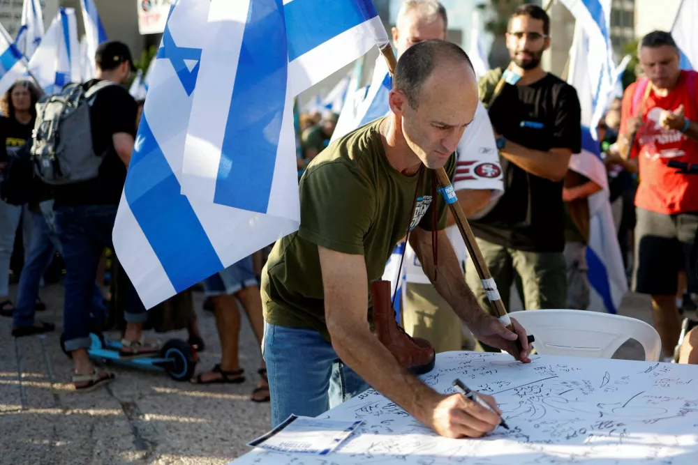 FILE PHOTO: An Israeli military reservist signs a pledge to suspend voluntary military service if the government passes judicial overhaul legislation, near the defence ministry in Tel Aviv, Israel, July 19, 2023. REUTERS/Amir Cohen/File Photo / Foto: Amir Cohen