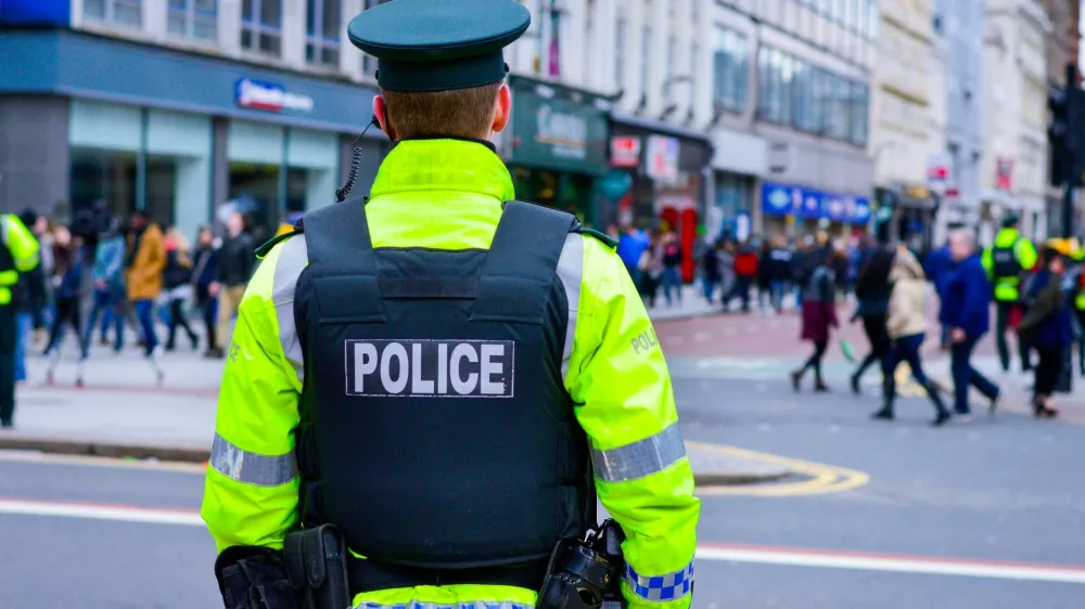 Belfast, Northern Ireland, UK, March 17, 2018. Back view of a policeman in a busy street at Belfast city centre during St Patrick's Day celebration, Northern Ireland.