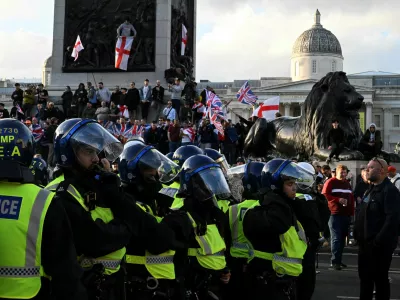Police officers stand guard next to supporters of British anti-immigration activist Stephen Yaxley-Lennon, also known as Tommy Robinson, during a rally, in London, Britain, September 13, 2025. REUTERS/Chris J. Ratcliffe