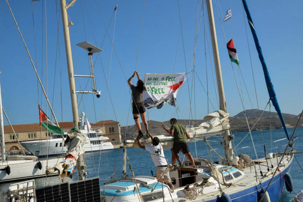 People hang a banner before the departure of the sailing boats Electra and Oxygen, part of the Global Sumud Flotilla, from the port of Ermoupolis on Syros island, Greece, September 14, 2025. REUTERS/Giorgos Solaris