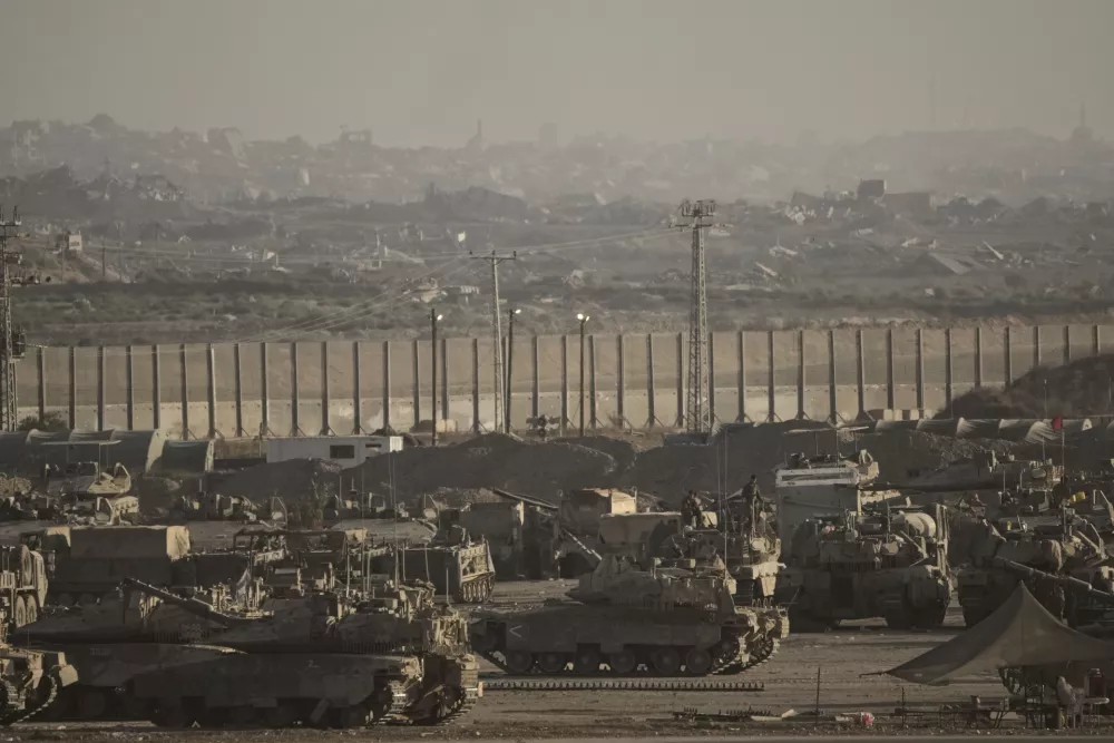 Israeli soldiers work on their tanks and armored personnel carriers (APC) at a staging area on the border with Gaza Strip, as seen from southern Israel, Tuesday, Sept. 16, 2025. (AP Photo/Leo Correa)