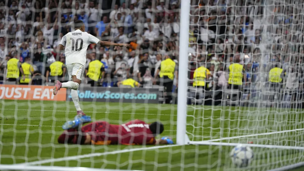 Real Madrid's Kylian Mbappe, top, celebrates after scoring past Marseille's goalkeeper Geronimo Rulli his side's second goal during a Champions League opening phase soccer match between Real Madrid and Marseille at Santiago Bernabeu stadium, in Madrid, Tuesday, Sept. 16, 2025. (AP Photo/Manu Fernandez)