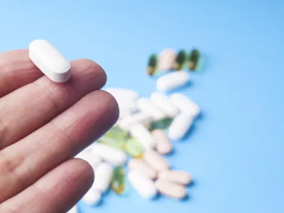 ﻿Medicine pills or capsules in hand, palm or fingers. Many pills and tablets. Pharmaceutical medicament, cure in container for health. Antibiotic, painkiller closeup.Many pills and tablets isolated on light blue background. Pharmaceutical medicament, cure in container for health. Antibiotic, painkiller and thermometer closeup.Many pills and tablets isolated on light blue background. Pharmaceutical medicament, cure in container for health. Antibiotic, painkiller and thermometer closeup.