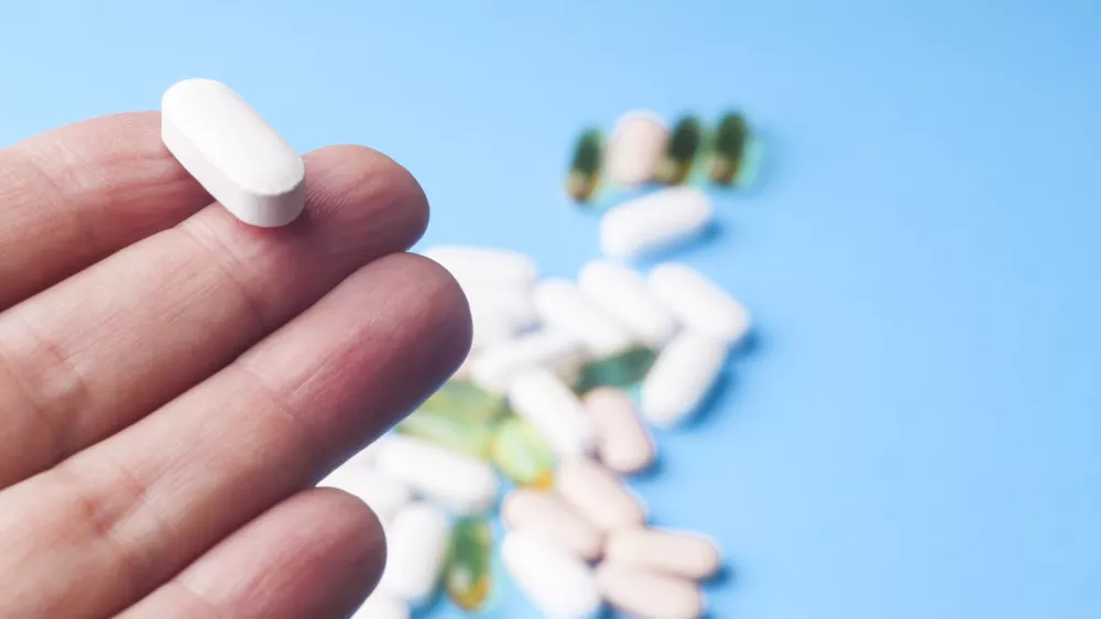 ﻿Medicine pills or capsules in hand, palm or fingers. Many pills and tablets. Pharmaceutical medicament, cure in container for health. Antibiotic, painkiller closeup.Many pills and tablets isolated on light blue background. Pharmaceutical medicament, cure in container for health. Antibiotic, painkiller and thermometer closeup.Many pills and tablets isolated on light blue background. Pharmaceutical medicament, cure in container for health. Antibiotic, painkiller and thermometer closeup.