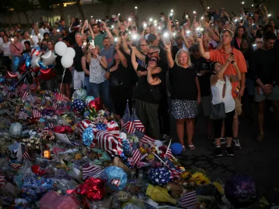 People light the flashlights of their mobile phones as they pray next to a tribute for slain conservative commentator Charlie Kirk at the headquarters of Turning Point USA, ahead of a memorial service for him which is to be held on September 21, in Phoenix, Arizona, U.S., September 20, 2025. REUTERS/Daniel Cole