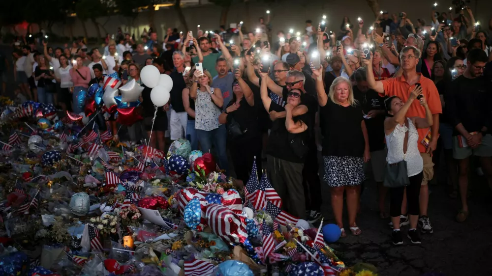 People light the flashlights of their mobile phones as they pray next to a tribute for slain conservative commentator Charlie Kirk at the headquarters of Turning Point USA, ahead of a memorial service for him which is to be held on September 21, in Phoenix, Arizona, U.S., September 20, 2025. REUTERS/Daniel Cole
