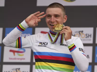 Belgium's Remco Evenepoel bites the gold medal after winning the men's elite individual time trial event, at the road cycling World Championships in Kigali, Rwanda, Sunday, Sept. 21, 2025. (AP Photo/Jerome Delay)