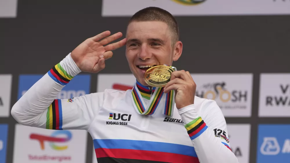 Belgium's Remco Evenepoel bites the gold medal after winning the men's elite individual time trial event, at the road cycling World Championships in Kigali, Rwanda, Sunday, Sept. 21, 2025. (AP Photo/Jerome Delay)