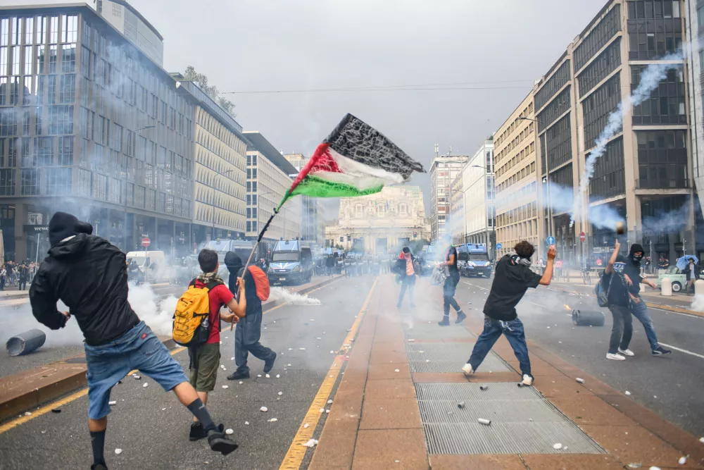 22 September 2025, Italy, Milan: Demonstrator hurl stones towards Police forces during clashes at a pro-palestine demonstration in Milan. A nationwide strike in solidarity with the people of Gaza caused disruptions across Italy on Monday. Photo: Claudio Furlan/LaPresse via ZUMA Press/dpa