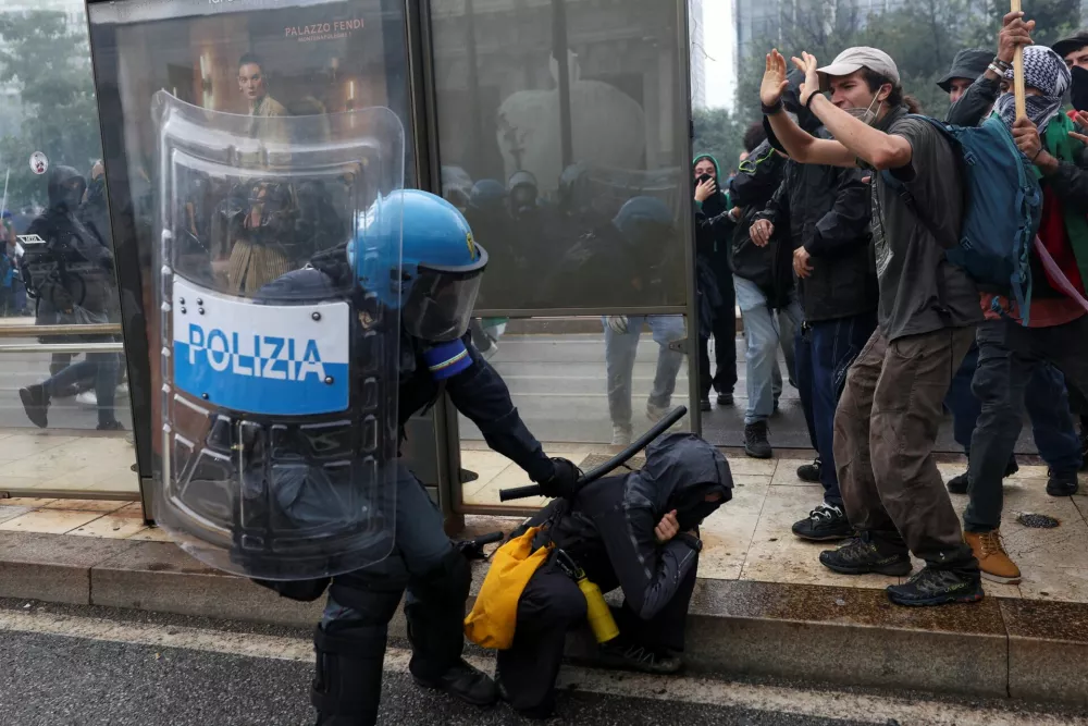 A police officer in riot gear hits a protester with a baton outside Milano Centrale railway station, at a demonstration that is part of a nationwide "Let's Block Everything" protest in solidarity with Gaza, with activists also calling for a halt to arms shipments to Israel, in Milan, Italy September 22, 2025. REUTERS/Claudia Greco