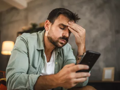 Portrait of adult furious man sit on chair and text sms on cellphone / Foto: Miljan Živković
