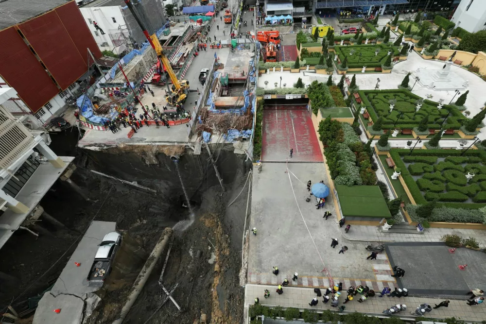 Emergency workers and people gather near a massive sinkhole that opened on Samsen Road near Vajira Hospital, in Bangkok, Thailand, September 24, 2025. REUTERS/Chalinee Thirasupa
