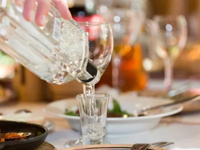 ﻿Feast in a restaurant, pouring vodka into the glass closeup
