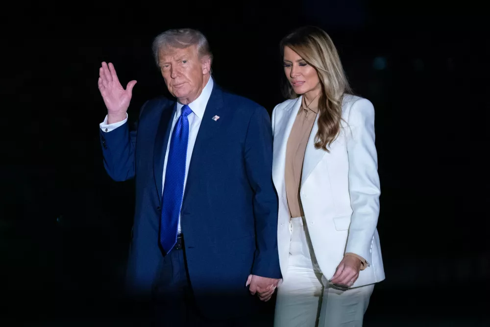 President Donald Trump holds hands with first lady Melania Trump as they walk on the South Lawn upon their arrival to the White House, in Washington, Tuesday, Sept. 23, 2025. (AP Photo/Jose Luis Magana)