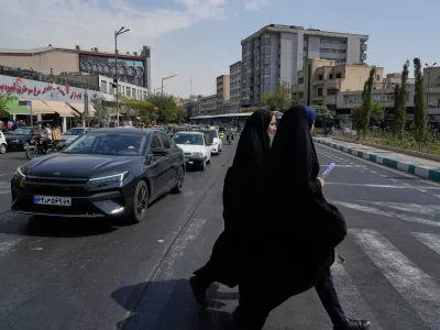 Two women cross the Enqelab-e-Eslami (Islamic Revolution) square, in Tehran, Iran, Saturday, Sept. 27, 2025. (AP Photo/Vahid Salemi)