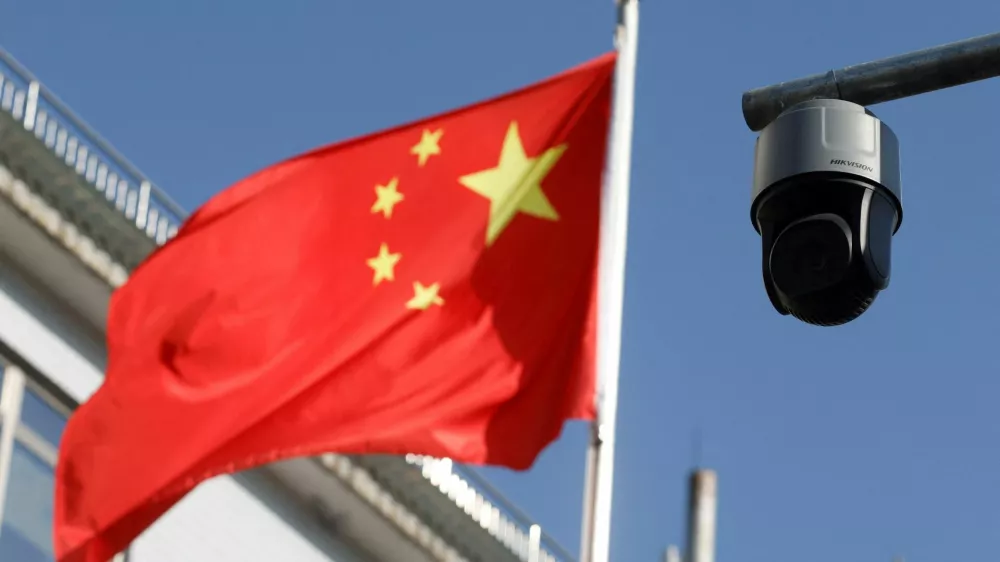 FILE PHOTO: A security surveillance camera overlooking a street is pictured next to a nearby fluttering flag of China in Beijing, China November 25, 2021. Picture taken November 25, 2021. REUTERS/Carlos Garcia Rawlins/File Photo