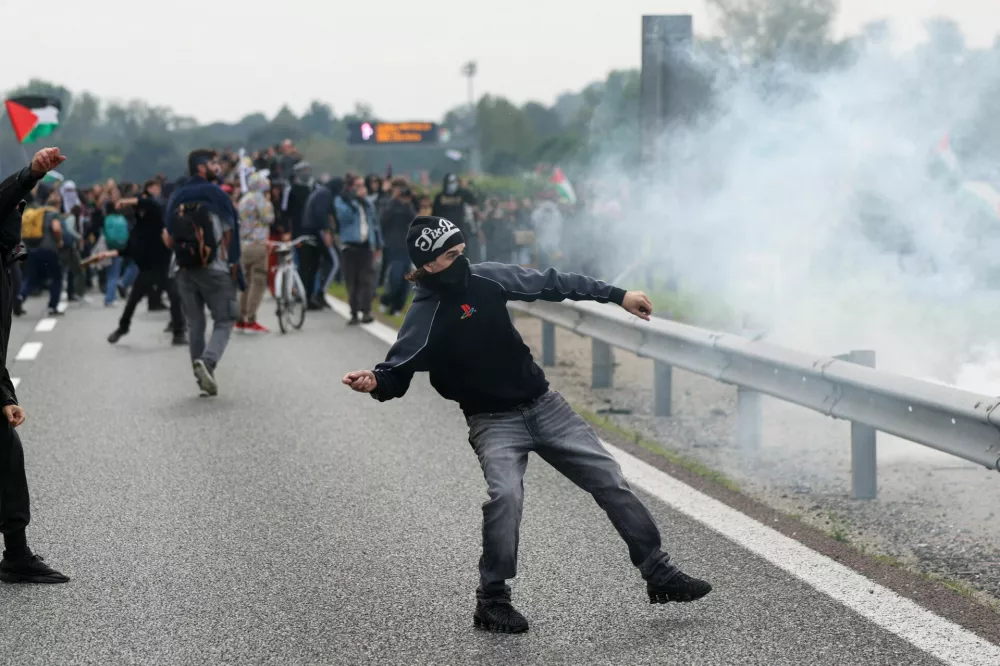 A pro-Palestinian protester throw an object at riot police at Milan's ring road during a nationwide strike called by the USB union to condemn the Israeli forces' interception of the Global Sumud Flotilla vessels aiming to reach Gaza and break Israel's naval blockade, in Milan Italy, October 3, 2025. REUTERS/Claudia Greco