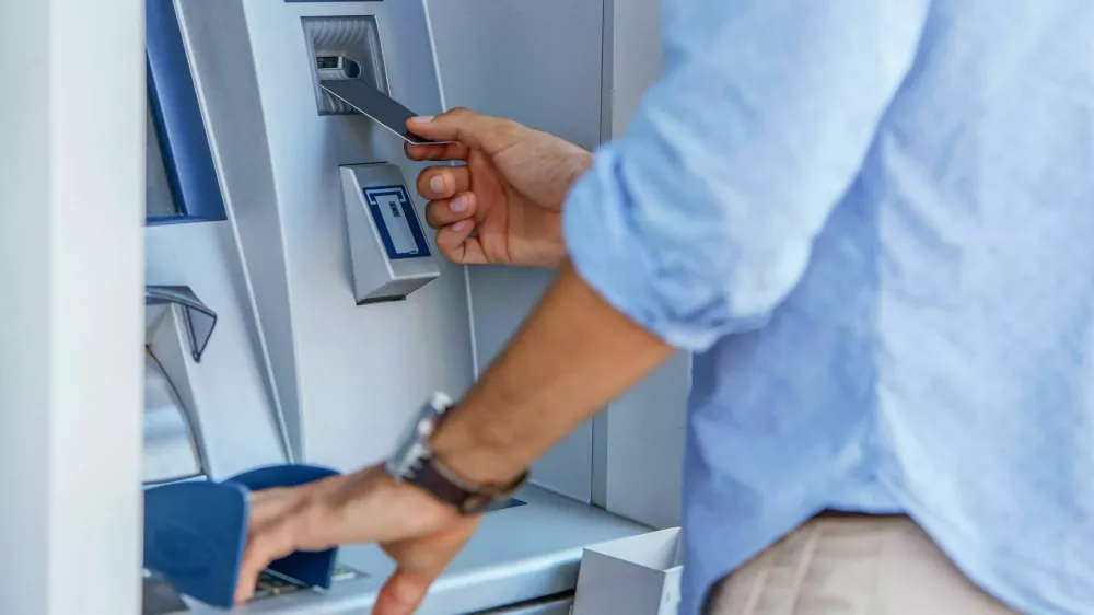 Man using a street ATM machine and withdrawing money, close up photo