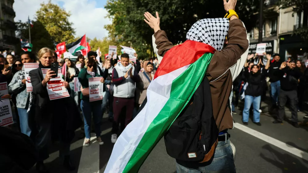 A protester wears a Palestinian flag over their shoulders during a demonstration in support of Palestinians, calling for an end to the war in Gaza, to condemn the Israeli forces' interception of the vessels of the Global Sumud Flotilla which were aiming to reach Gaza and break Israel's naval blockade, and for the release of the crews, in Paris, France, October 4, 2025. REUTERS/Stephane Mahe