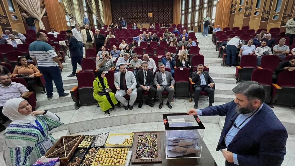A Syrian electoral college member, right, casts his vote during the parliamentary elections at Latakia's Governor ballot station, in the coastal city of Latakia, Syria, Sunday, Oct. 5, 2025. (AP Photo/Hussein Malla)