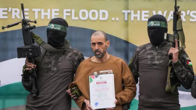 FILE - Israeli captive, Eli Sharabi, who has been held hostage by Hamas in Gaza since October 7, 2023, stands on a stage escorted by Hamas fighters before being handed over to the Red Cross in Deir al-Balah, central Gaza Strip, Saturday Feb. 8, 2025. (AP Photo/Abdel Kareem Hana, File)