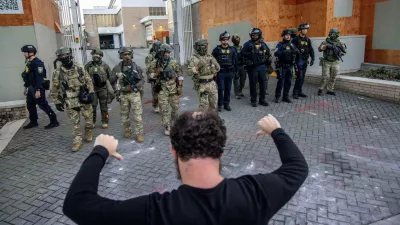 A protester stands off against police and federal officers at a U.S. Immigration and Customs Enforcement facility in Portland, Ore. on Sunday, Oct. 5, 2025. (AP Photo/Ethan Swope)