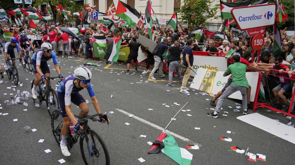 Riders of the Israel Premier Tech team compete as people holding Palestinian flags try to disrupt the eleventh stage of the Spanish Vuelta cycling race, from Bilbao to Bilbao, Spain, Wednesday, Sept. 3, 2025. (AP Photo/Miguel Oses)