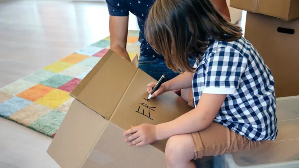 Deček, ki na škatlo zapisuje svoje ime. / Foto: Istock