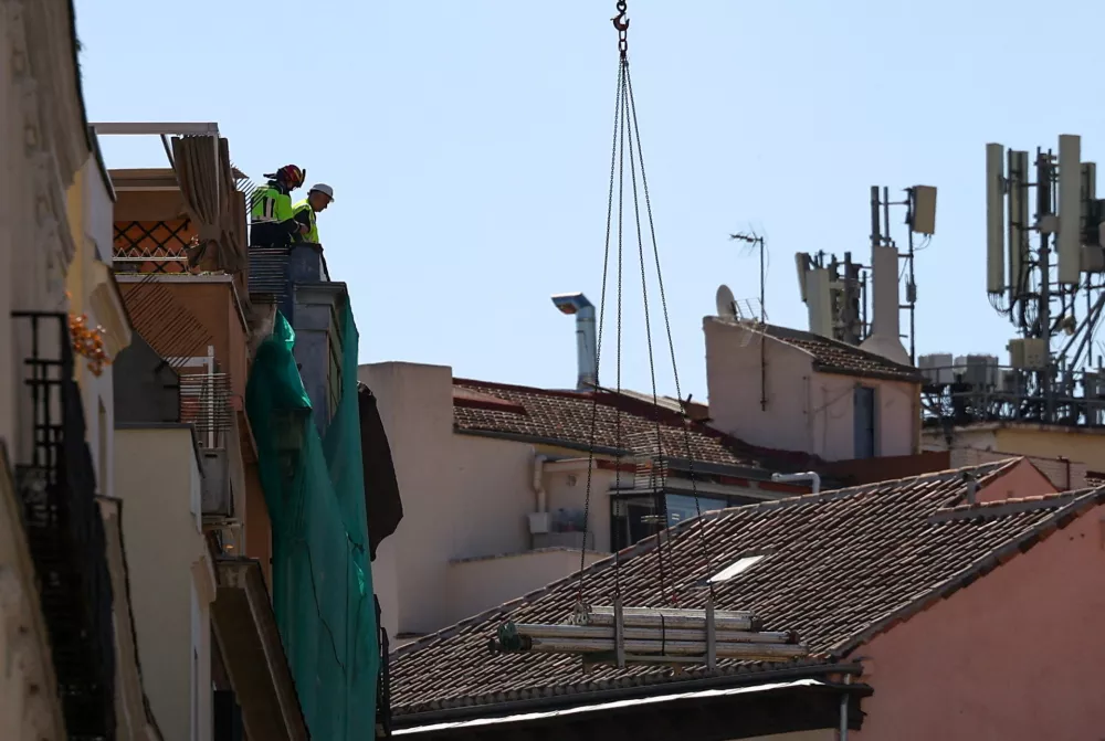 Workers stand on a building at the site of a collapse in central Madrid, Spain, October 7, 2025. REUTERS/Juan Medina