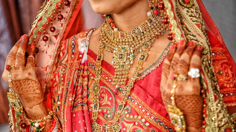 Indijsko nevesto med poročnim obredom krasi zlat nakit. f iStock
