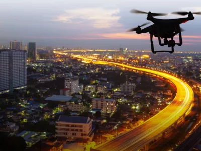 Silhouette of drone flying above city at sunset