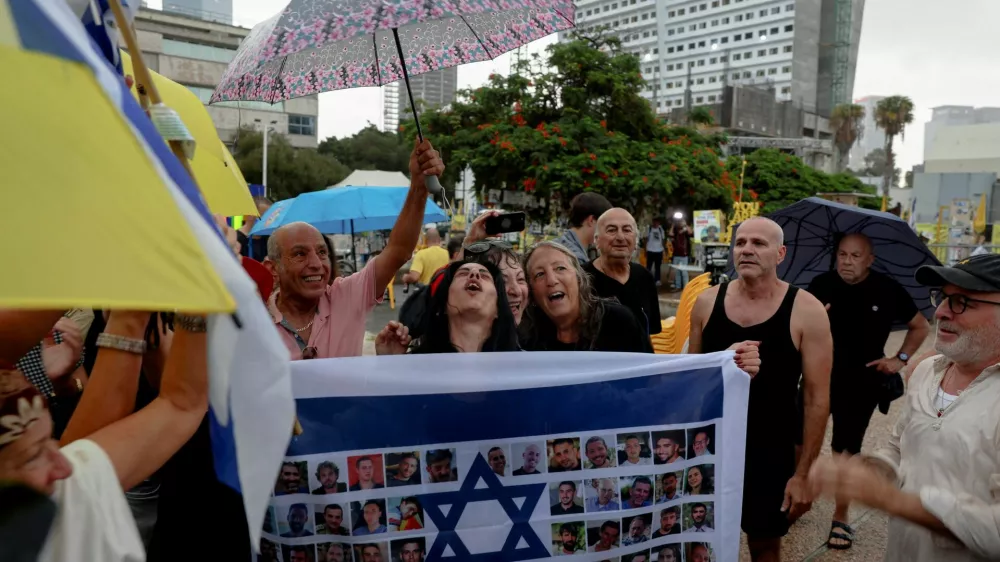 Einav Zangauker, the mother of hostage Matan Zangauker, reacts holding an Israeli flag with photos of hostages, after U.S. President Donald Trump announced that Israel and Hamas agreed on the first phase of a Gaza ceasefire, at the "Hostages square", in Tel Aviv, Israel, October 9, 2025. REUTERS/Ronen Zvulun