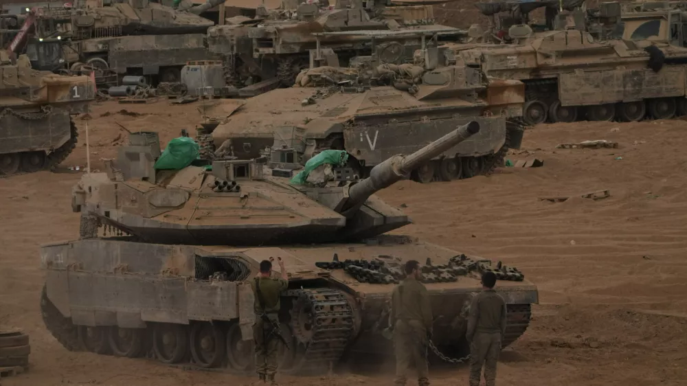Israeli soldiers work on a tank near the Israeli-Gaza border, as seen from southern Israel, Thursday, Oct. 9, 2025, following the announcement that Israel and Hamas have agreed to the first phase of a peace plan to pause the fighting. (AP Photo/Ariel Schalit)