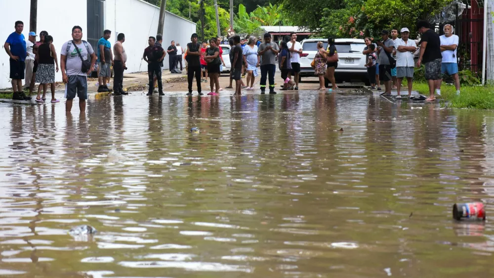 People look at a flooded street after torrential rains that caused an overflow of rivers in Poza Rica, Veracruz state, Mexico, October 10, 2025. REUTERS/Rolando Ramos