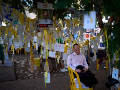 A man rests at a plaza known as hostages square, in Tel Aviv, Israel, Sunday, Oct. 12, 2025. (AP Photo/Emilio Morenatti)
