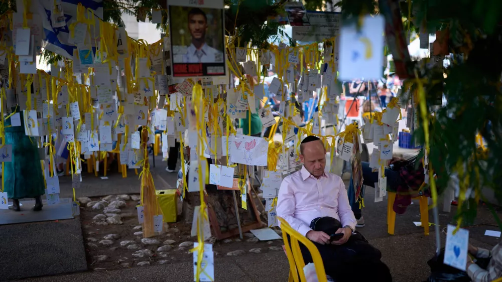 A man rests at a plaza known as hostages square, in Tel Aviv, Israel, Sunday, Oct. 12, 2025. (AP Photo/Emilio Morenatti)